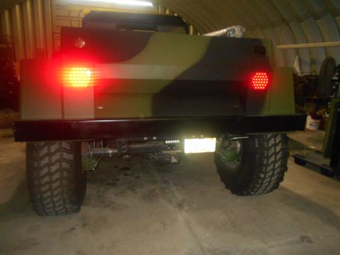 1992 Ford Bronco - This camouflage SUV is seen from the rear, bright red taillights and tires.
