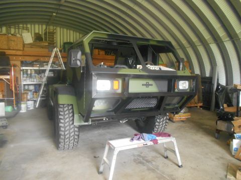 1992 Ford Bronco - A military-style truck is parked in a garage, appearing to be under repair or modification.