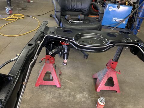 1979 Jeep CJ5 - The frame of a 1979 Jeep CJ5 is supported by jack stands in a workshop setting.