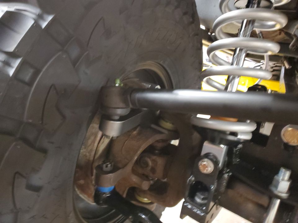 close-up of vehicle's front wheel, tie rod, and coilover shock assembly