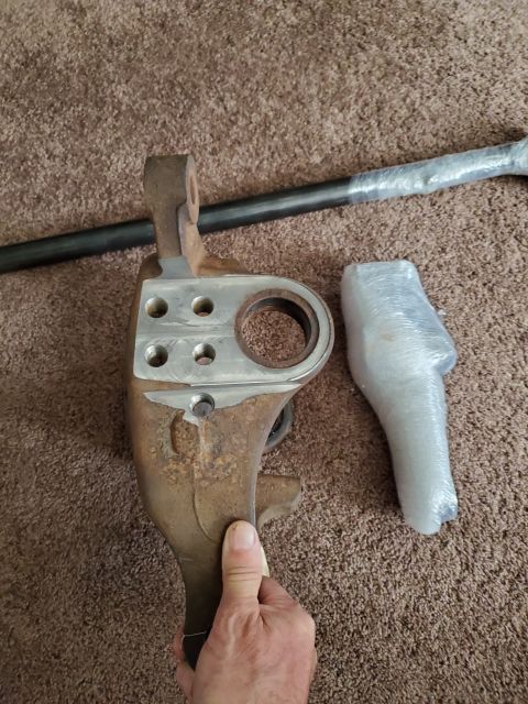 1996 Ford Bronco - A steering knuckle and tie rod are displayed on a carpeted surface.