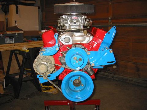 1985 Ford Bronco - A colorful engine assembly is displayed on a stand in a garage setting.