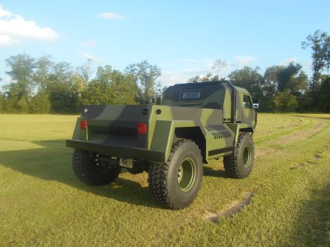 1992 Ford Bronco - This heavily modified truck features a camouflage paint scheme and a utilitarian bed, seen from the rear.