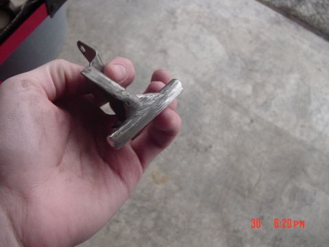 1987 Ford Bronco - A metal bracket is held in a hand against a concrete background, with a Supermotors.net watermark visible.