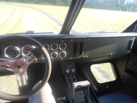 1992 Ford Bronco - The interior of a vehicle shows a custom steering wheel and a dashboard filled with gauges, suggesting a modified or specialized build.