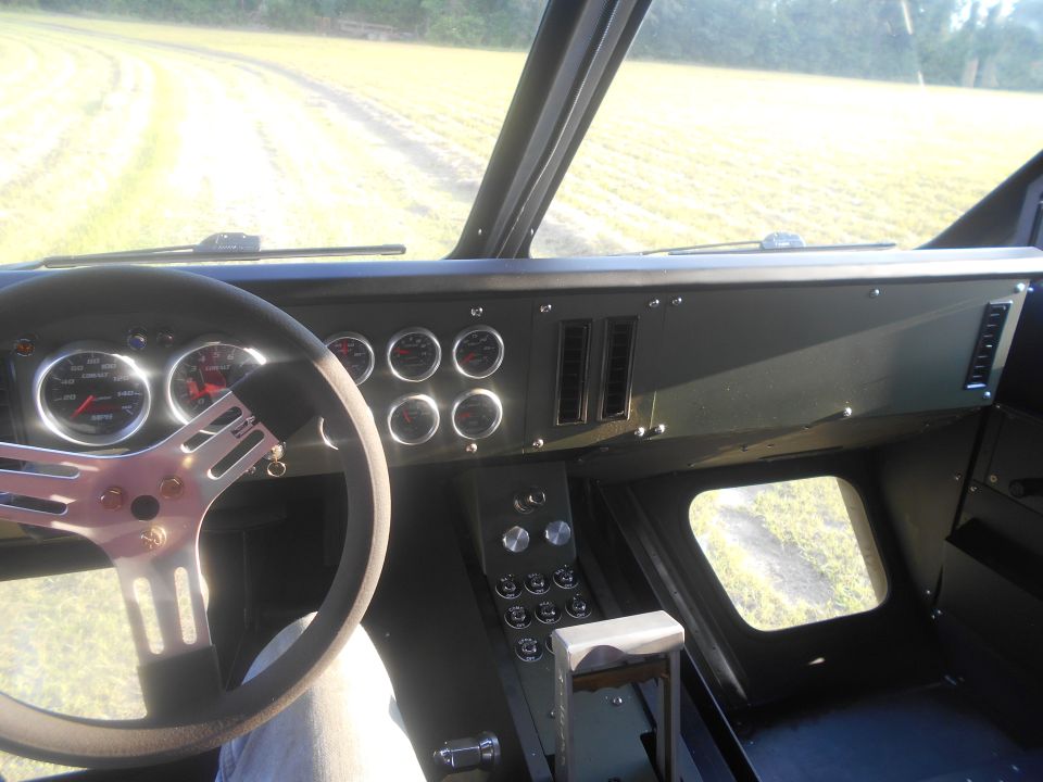 Interior view of a vehicle with a custom steering wheel and numerous gauges on the dashboard