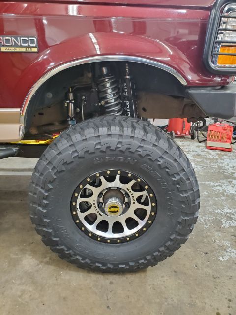 1996 Ford Bronco - Close-up of a red 1996 Ford Bronco's front fender and wheel assembly, aftermarket Method wheels and Toyo Open Country tires.
