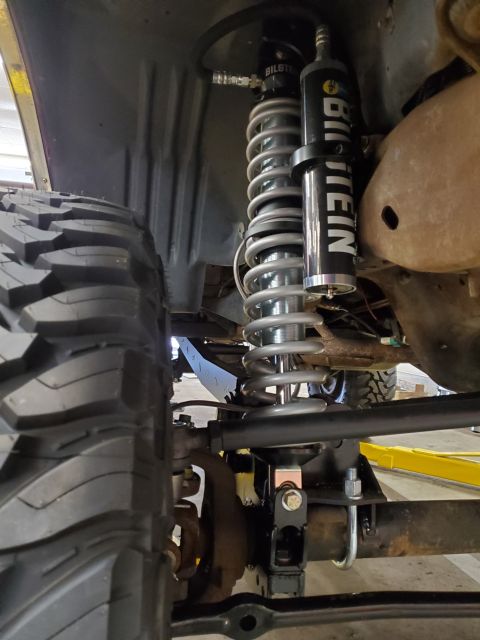1996 Ford Bronco - Custom suspension components, including a Bilstein shock and coil spring, are visible next to a large tire.