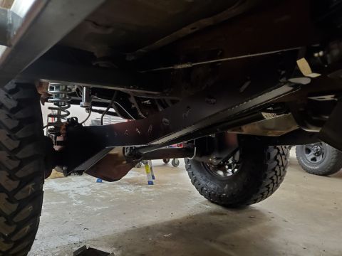 1996 Ford Bronco - The undercarriage of a modified SUV shows heavy-duty suspension components and large tires.