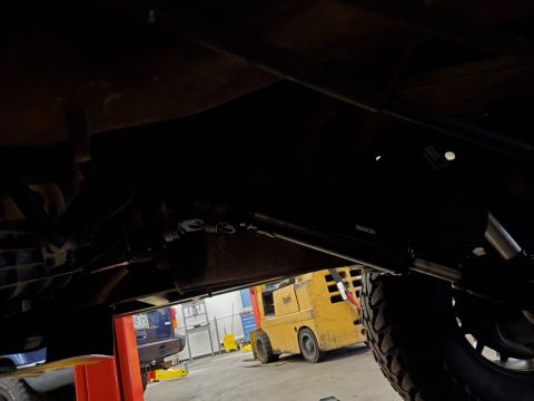1996 Ford Bronco - Underside view of a vehicle on a lift, with a forklift visible in the background.