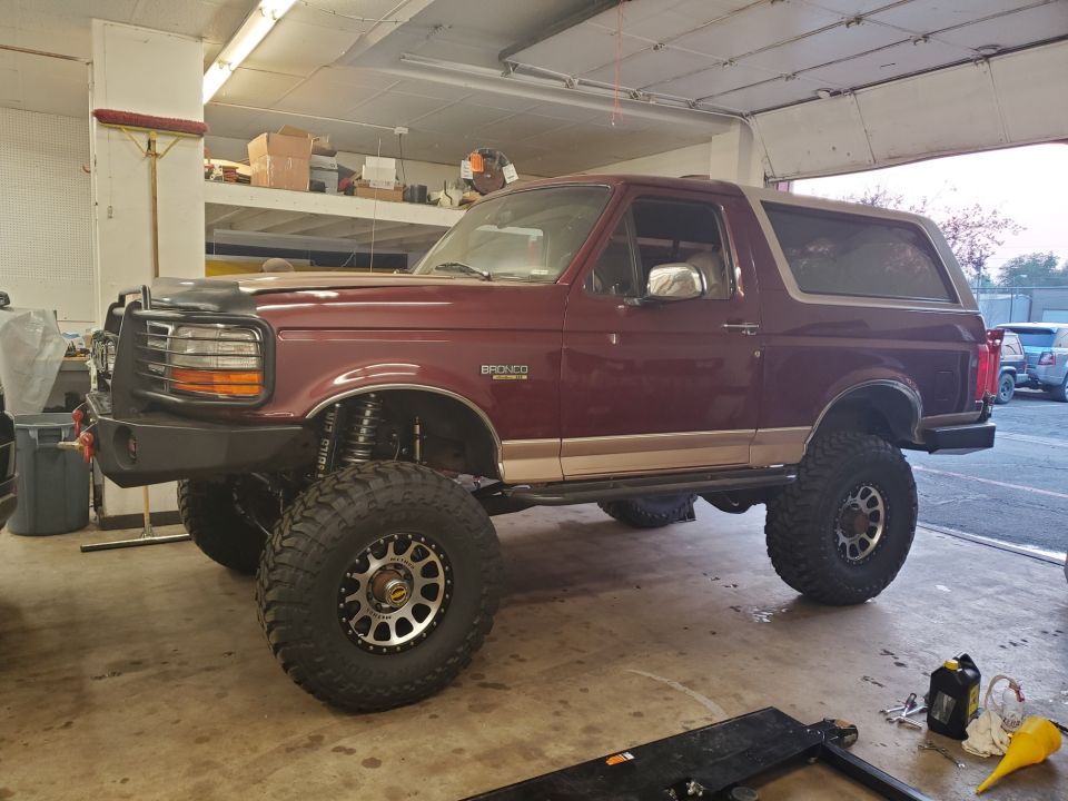 Maroon 1996 Ford Bronco with lifted suspension and large off-road tires