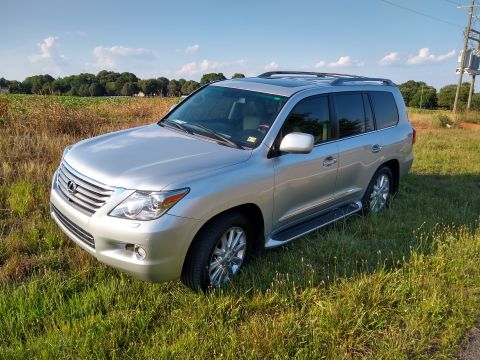 2008 Lexus LX 470 - This Lexus SUV is parked off-road in a field under a partly cloudy sky.