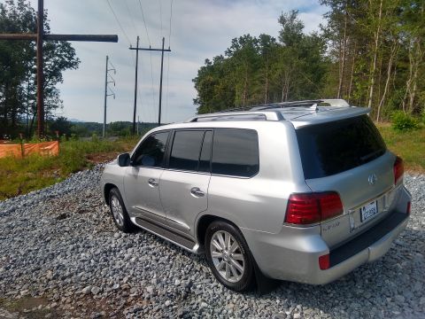 2008 Lexus LX 470 - This 2008 Lexus LX 470 is seen from its rear-right quarter, parked on a gravel surface with trees and utility poles in the background.