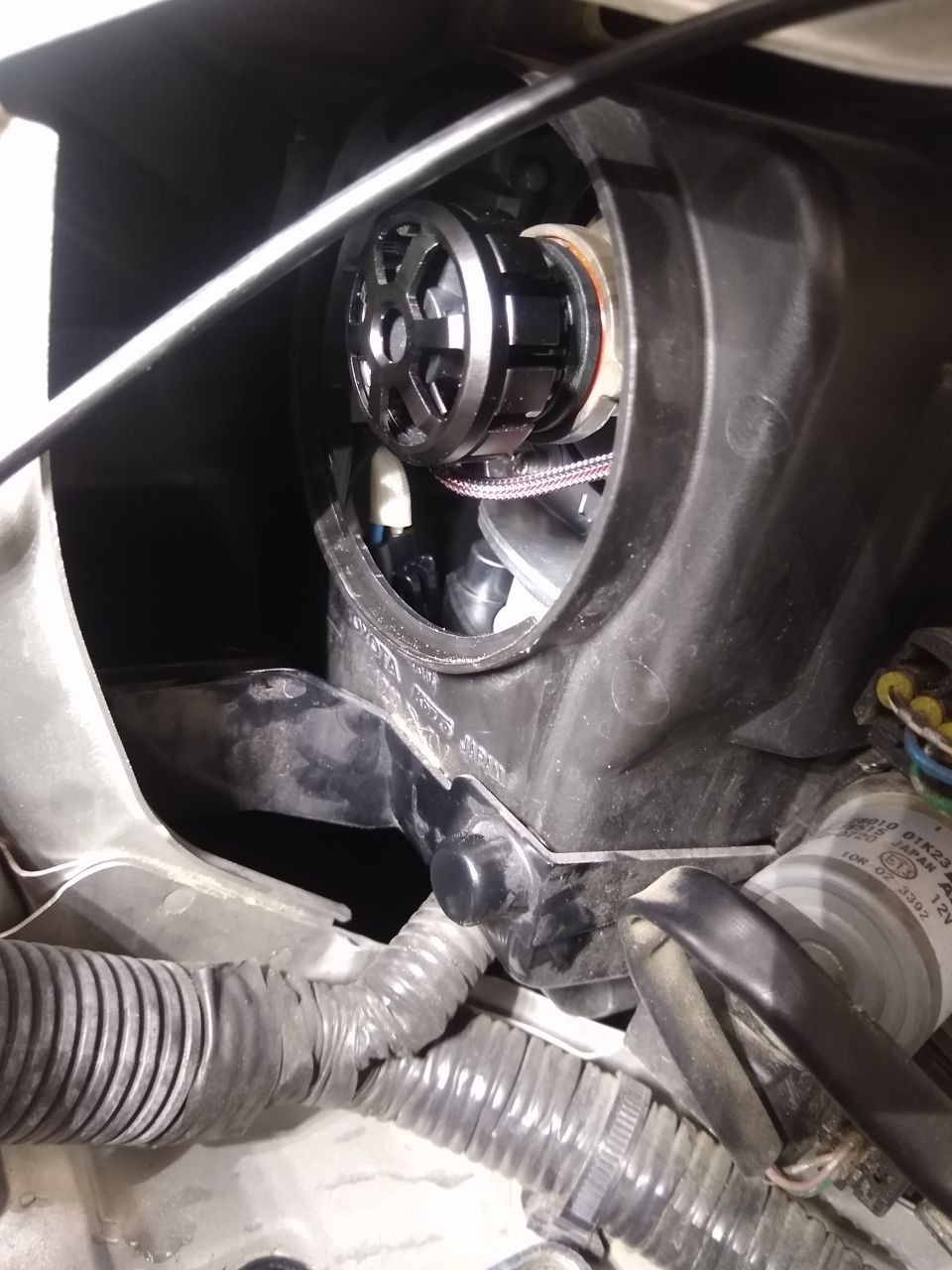 Close-up of a car headlight assembly with a new LED bulb installed. Wiring and housing visible