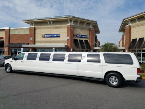 2000 Ford Excursion - A long white limousine, based on a 2000 Ford Excursion, is parked outside a commercial building.