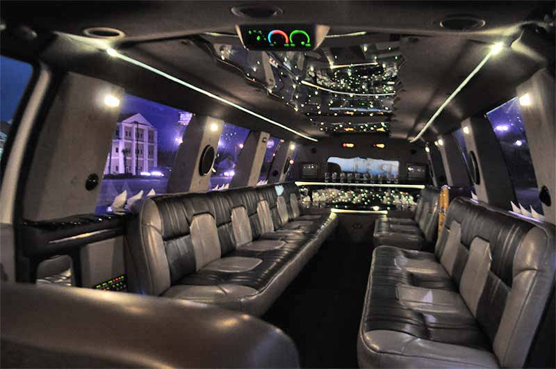 Interior of a stretched limousine with leather seats, mirrored ceiling with star lights, and a bar area