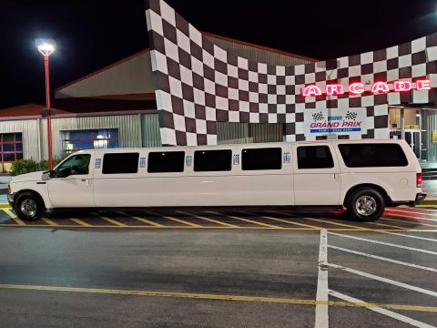 2000 Ford Excursion - A long white limousine is parked outside an arcade building at night.