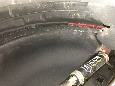 2014 Ford F-150 - Close-up of a vehicle's wheel well liner, showing an Icon Vehicle Dynamics shock absorber and part of the suspension.