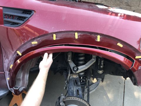 2014 Ford F-150 - Installing a fender flare on a red Ford SVT Raptor, revealing the suspension components and wheel well.