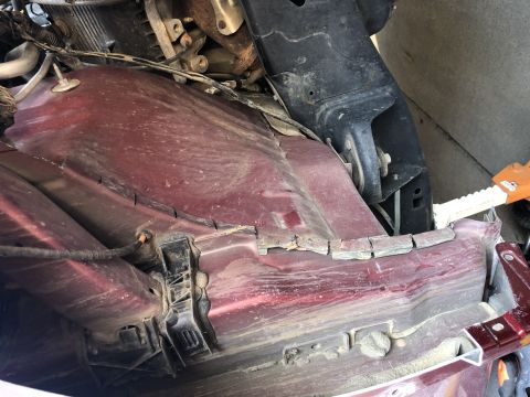 2014 Ford F-150 - Close-up view of the undercarriage of a red vehicle, showing suspension parts and wiring harnesses.