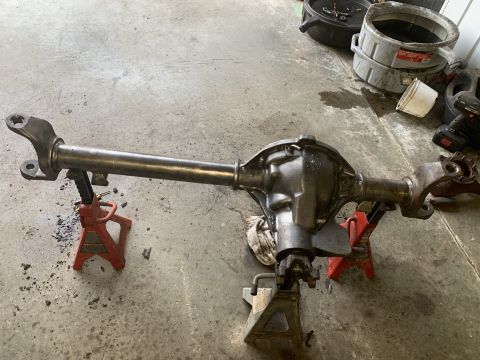 1979 Jeep CJ5 - A disassembled rear axle assembly rests on red and black jack stands in a garage setting.