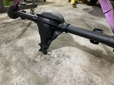 1979 Jeep CJ5 - A black rear axle assembly is suspended by straps in a workshop setting.