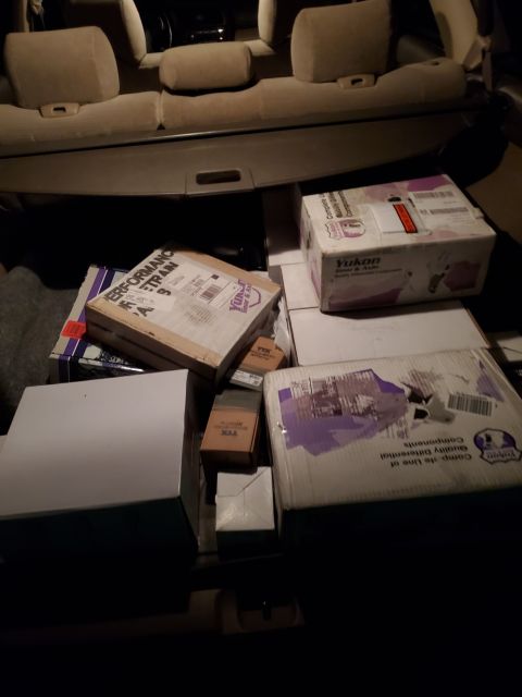 1996 Ford Bronco - Boxes of automotive parts are piled in the cargo area of a vehicle.