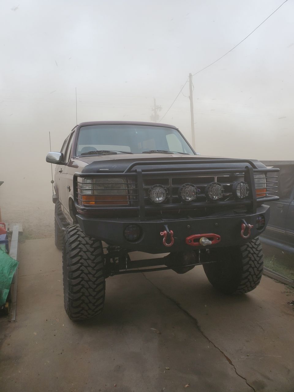1996 Ford Bronco with aftermarket front bumper, winch, and KC lights. Lifted with large off-road tires