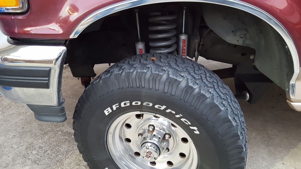 Maroon Ford Bronco front driver's side tire and fender well with Rough Country shocks.