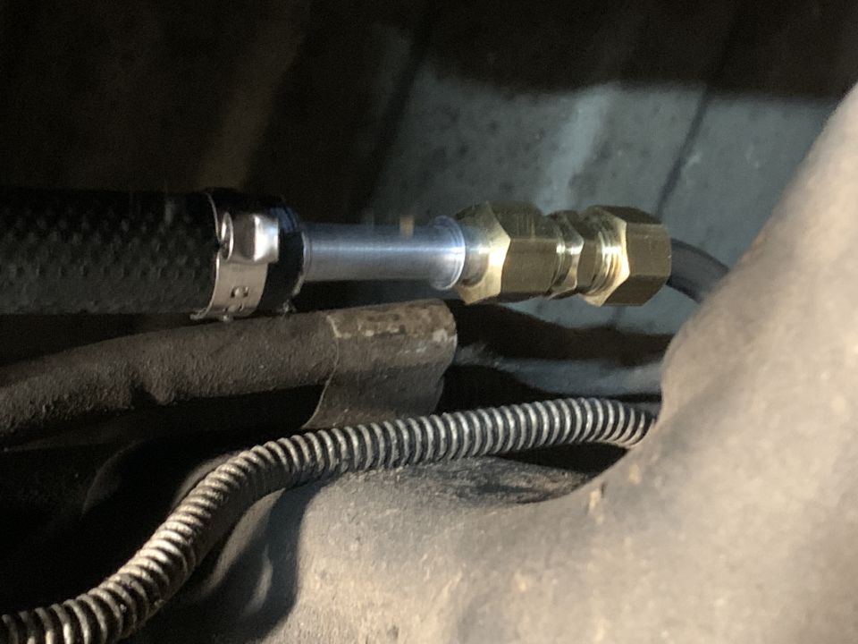 Brass quick-disconnect fitting joining a steel line and braided hose underneath a vehicle
