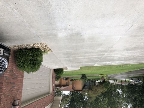 1995 Mercury Grand Marquis - A dark-colored vehicle is partially visible on the left side of the image, parked in a driveway next to a brick garage. The driveway appear…
