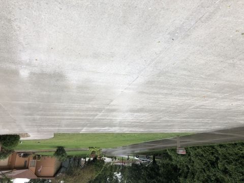 1995 Mercury Grand Marquis - A wet concrete driveway and lawn are visible in the foreground, with a portion of a house and trees in the background. A silver sedan is pa…
