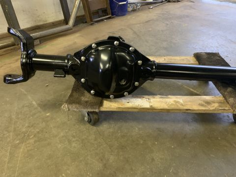 1979 Jeep CJ5 - A black rear axle assembly, likely from a Jeep CJ, is shown resting on a wooden pallet with wheels. The differential cover is prominently v…