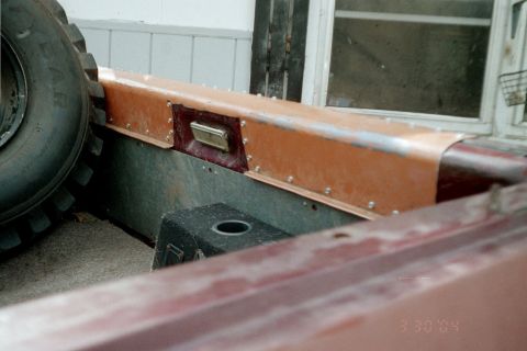 1979 Ford Bronco - Close-up of the interior of a vehicle, showing a large tire and copper-colored trim panel with rivets.