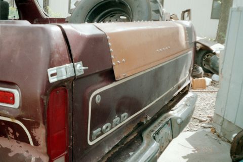 1979 Ford Bronco - Rear view of a 1979 Ford Bronco showing the tailgate and a camper shell, with a spare tire mounted above.