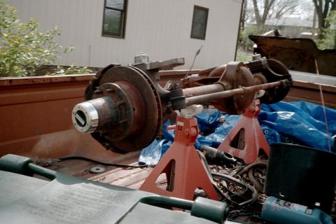 1979 Ford Bronco - A rusty front axle assembly is stored in the bed of a pickup truck.