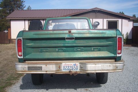 1977 Ford F-150 - Rear view of a green 1977 Ford F-150 pickup truck with a spare tire in the bed.