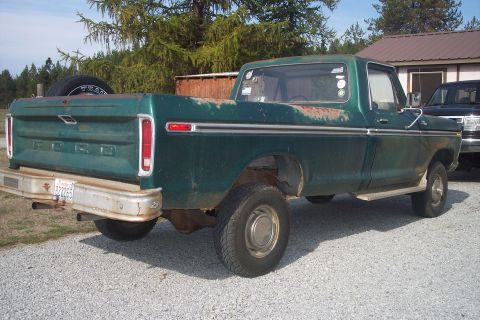 1977 Ford F-150 - This green Ford F-150 pickup truck shows signs of rust and wear, with a spare tire in the bed.