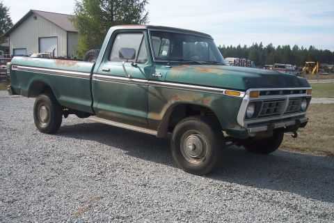 1977 Ford F-150 - This green 1977 Ford F-150 pickup truck shows signs of wear and tear, including rust on the hood and bed.