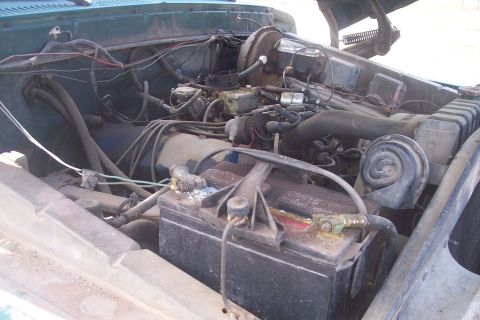 1977 Ford F-150 - The engine bay of a 1977 Ford F-150 reveals its mechanical components, including the battery and carburetor.