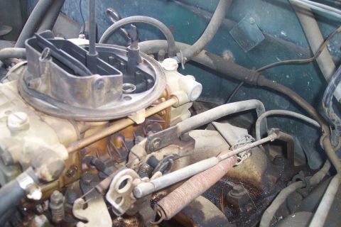 1977 Ford F-150 - Close-up view of an engine's carburetor and associated mechanical components.