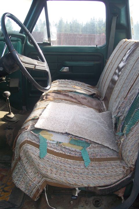 1977 Ford F-150 - The interior of a truck shows significant wear on the driver's seat and dashboard.