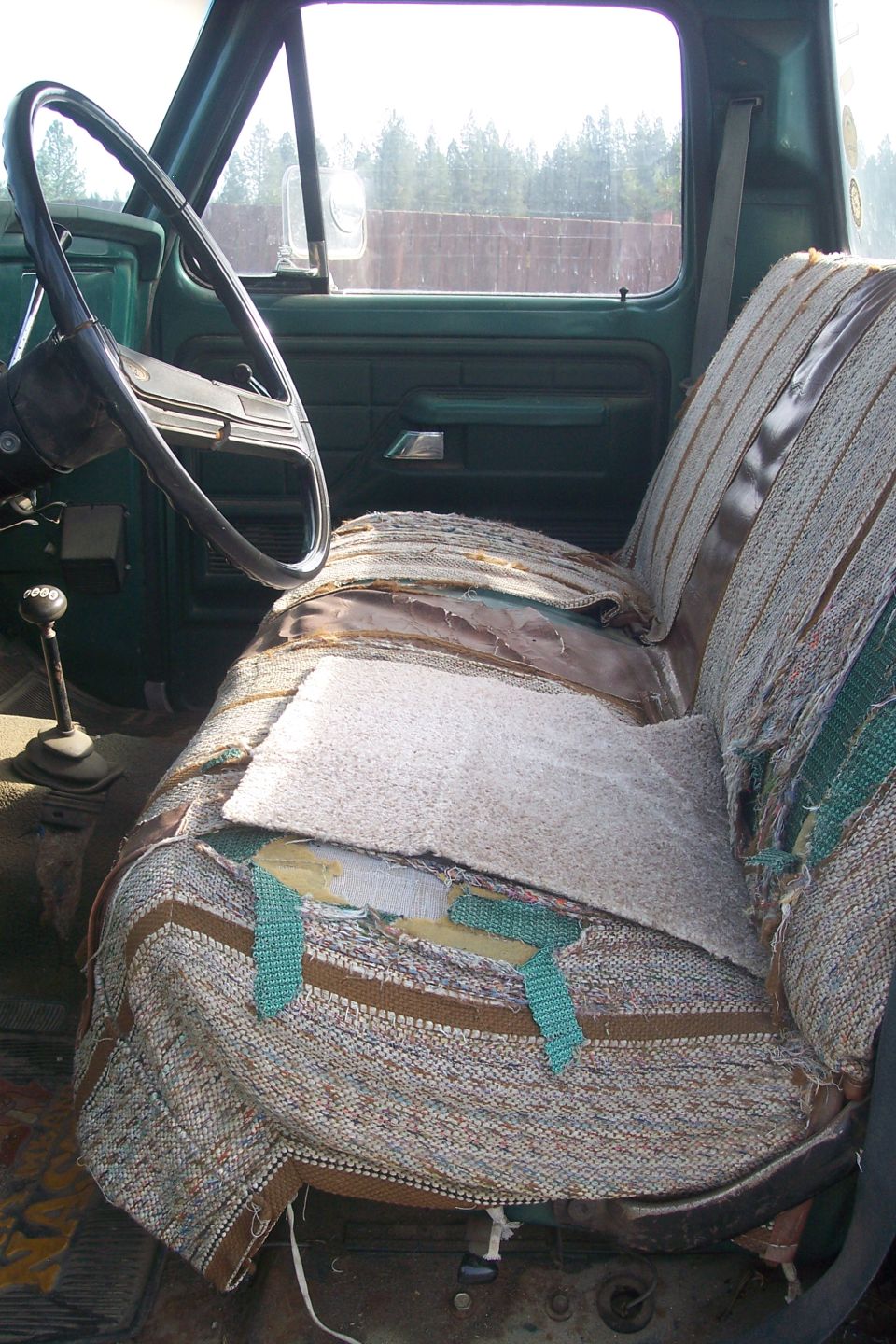 Truck interior showing ripped seat, steering wheel, and gear shift