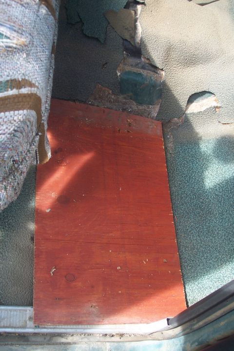 1977 Ford F-150 - The interior floor shows significant wear, with torn upholstery and a makeshift plywood patch.