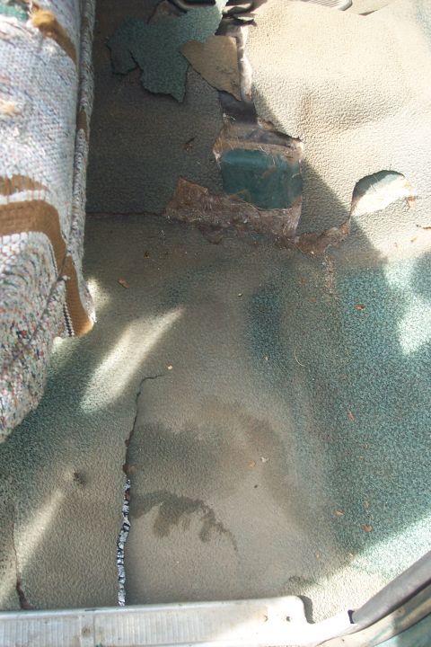 1977 Ford F-150 - Interior floor shows significant wear and tear with exposed metal and damaged carpet.
