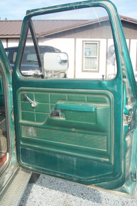 1977 Ford F-150 - Interior view of a green 1977 Ford F-150 door panel, showing the window crank and armrest.