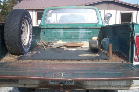 1977 Ford F-150 - Rear view of a 1977 Ford F-150 pickup truck bed, showing a spare tire and some debris.