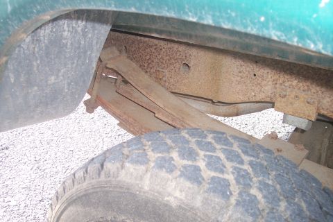 1977 Ford F-150 - Close-up of the undercarriage of a truck, showing the leaf spring and frame.