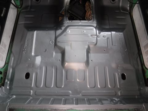 1992 Ford Bronco - The interior floor pan of a vehicle shows signs of rust repair and structural modifications.
