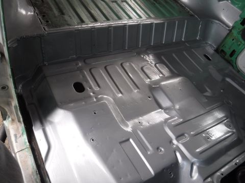 1992 Ford Bronco - The interior floor pan of a vehicle, showing primer application and structural details.